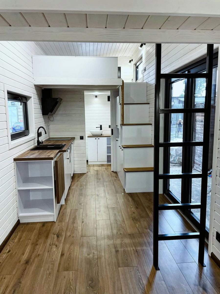 Tiny home interior — kitchen with ladder access to loft